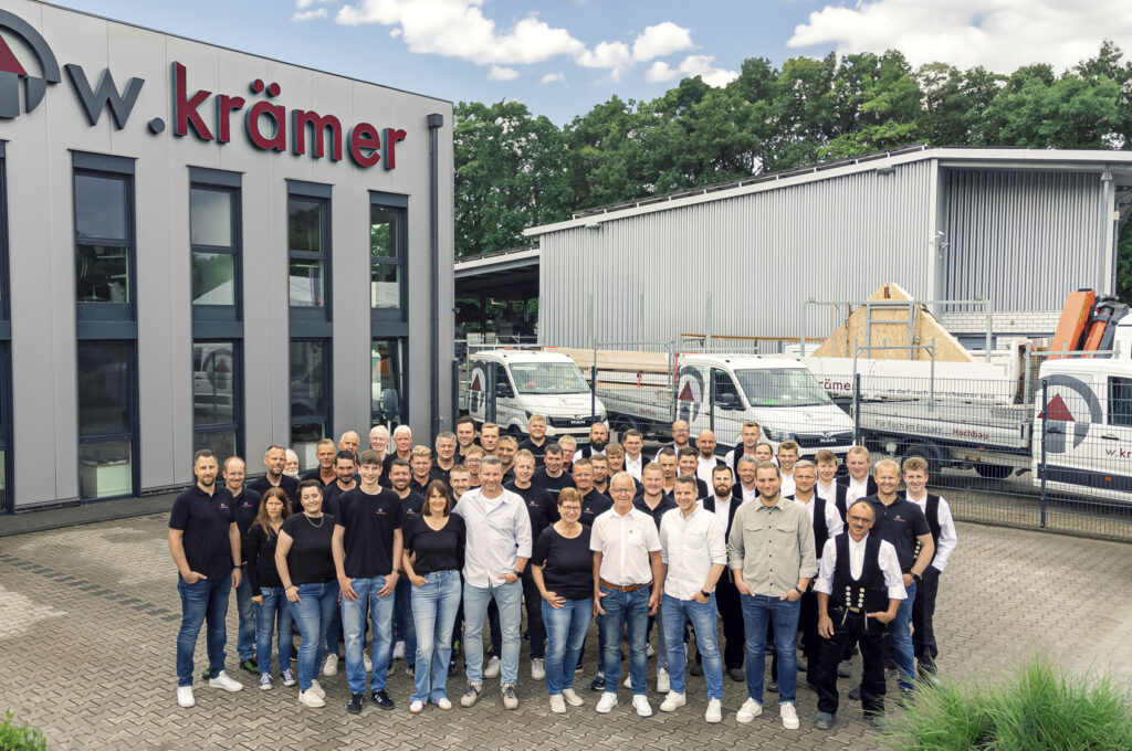 Gruppenfoto des Teams des Werner Krämer Bauunternehmens vor einer Baustelle, zeigt die familiäre Atmosphäre und professionelle Expertise.