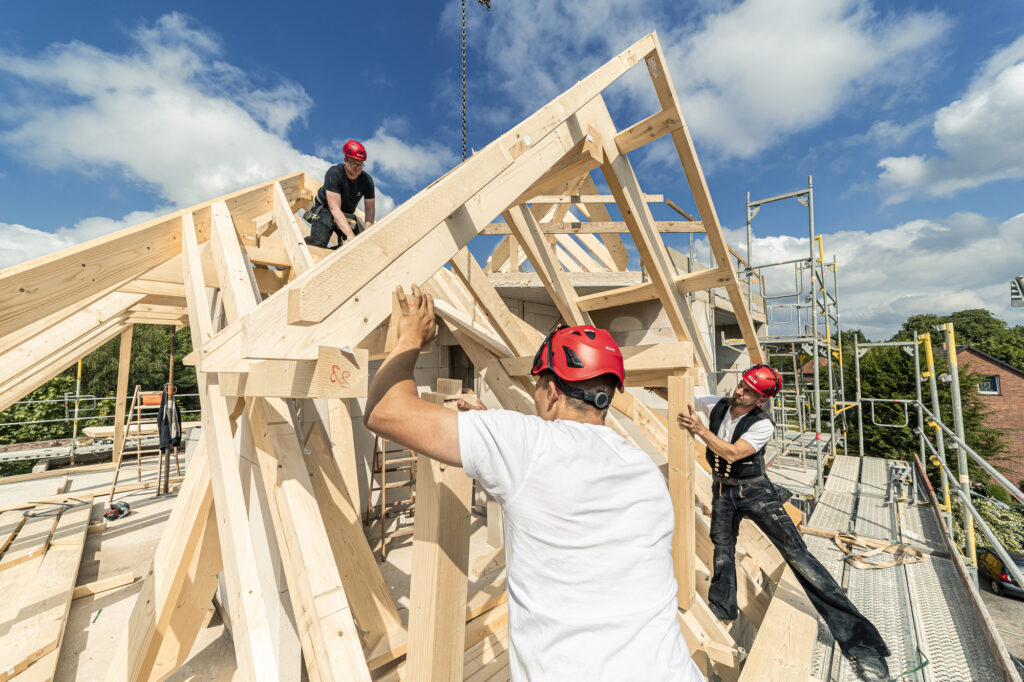 Zimmerer beim aufstellen einer Dachkonstruktion aus Holz